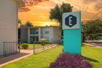 Charming apartment complex with vibrant exterior, lush landscaping, and a stunning sunset backdrop at Establishment Apartments.