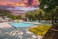 Stunning pool area with vibrant yellow loungers and palm trees, set against a dramatic sunset sky, creates a tropical paradise.