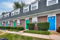 The front view of Bright Meadows Townhomes showcasing inviting green doors on the apartment building's exterior.