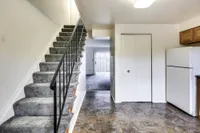 Welcoming kitchen with a refrigerator, stove, and stairs, leading into Bright Meadows Townhomes.