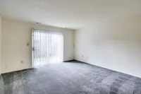 Bright Meadows Townhomes living room featuring an empty space with carpet and a sliding glass door letting in natural light.