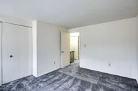 Inviting bedroom in Bright Meadows Townhomes, showcasing plush carpet and fresh white walls for a serene vibe.