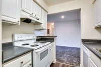 Modern kitchen with white cabinets and a stove top oven, located in the living area of Allyson Gardens Apartments II.