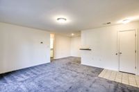 An inviting empty room with a cozy carpet and pristine white walls, part of Allyson Gardens Apartments II.