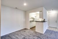 A clean, empty kitchen area with white cabinets, located in the living room of Allyson Gardens Apartments II.