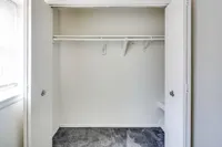 A bright bedroom closet with a white door, set against a soft gray carpet in Bright Meadows Townhomes.