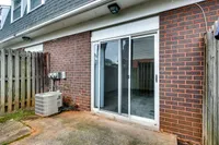 A cozy brick patio at Bright Meadows Townhomes featuring a sliding glass door and a surrounding fence.