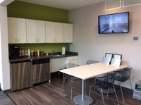 A bright kitchen in Bright Meadows Townhomes featuring a refrigerator, microwave, and a television for entertainment.