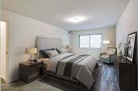 A well-organized bedroom in Allyson Gardens Apartments, complete with a bed, desk, and nightstand for a serene environment.