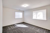 An inviting empty room at Allyson Gardens Apartments II, complete with a plush carpet and a window for natural illumination.