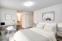Stylish bedroom at Allyson Gardens Apartments II with a comfortable bed, a desk for work, and a wall-mounted television.