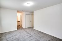 A spacious empty room featuring a soft carpet and clean white walls at Allyson Gardens Apartments II.