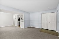 Bright and inviting open living area with neutral tones, plush carpeting, and a modern kitchen alcove. Features ample natural light and sleek closet space.