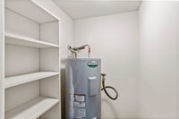 Efficient utility room featuring a brand-new water heater and convenient built-in shelving for optimal storage.