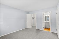 Bright and airy bedroom featuring plush carpeting, a walk-in closet, and an en-suite bathroom with modern fixtures.