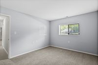 Bright, spacious room with soft carpet flooring and a large window inviting natural light, creating a warm, inviting atmosphere.