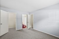 Bright and spacious bedroom featuring neutral walls, plush carpet, and a glimpse of an en-suite bathroom through an open door.