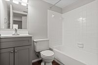 Elegant bathroom with sleek vanity, pristine white tiles, and a modern bathtub, offering a serene and stylish space.
