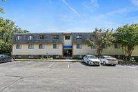 Charming residential apartment building with ample parking and lush greenery, ideal living environment.