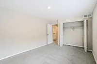Spacious bedroom with plush carpet, ample closet space, and soft natural lighting creating a cozy ambiance.