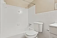 Bright and modern bathroom featuring a pristine white subway-tiled shower and bath combo, complemented by a sleek toilet and vanity unit.