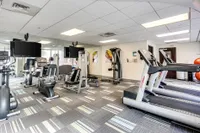 Contemporary fitness center equipped with treadmills, weight machines, and exercise equipment, featuring bright lighting and modern decor.