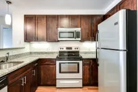 Contemporary kitchen with sleek stainless steel appliances, elegant dark wood cabinets, and polished granite countertops.