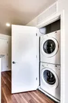Modern apartment laundry area with a sleek stacked washer and dryer set against elegant hardwood floors.