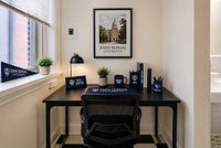 Charming study nook with university decor, featuring a sleek black desk, comfortable chair, and framed university artwork.