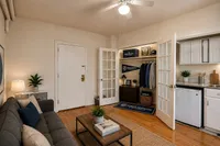 Charming studio apartment showcasing a cozy living area, open closet, and compact kitchen with modern cabinetry, perfect for urban living.