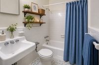 Charming bathroom with elegant white tiles, accented by a stylish blue curtain, featuring lush green plants and warm wooden shelves.