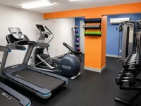 Modern apartment gym with state-of-the-art equipment, vibrant decor, and diverse workout options.