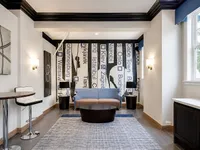 Contemporary lounge area with chic city-themed mural, stylish seating, and modern decor in a bright, inviting space.