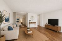 Bright and inviting living space featuring modern decor, a cozy beige sofa, wooden coffee table, and a sleek TV stand, perfect for relaxation and entertainment.