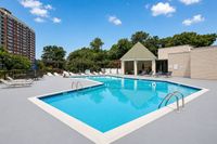 Inviting outdoor pool area with sparkling blue water, surrounded by lush greenery and modern lounge chairs, perfect for relaxation and leisure.