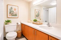 Inviting and bright bathroom with elegant wood cabinetry, large mirror, and modern decor, perfect for serene relaxation.