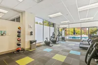 Modern fitness center with state-of-the-art equipment, vibrant flooring, and large windows overlooking a pool area.