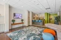 Modern lounge area featuring stylish decor with a patterned rug, elegant seating, and a vibrant bar with blue stools.