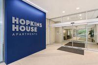 Inviting entrance of Hopkins House Apartments featuring elegant blue signage and modern glass doors.