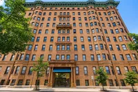 Majestic historic brick apartment building with charming architectural details, framed by lush green trees, promising elegant urban living.