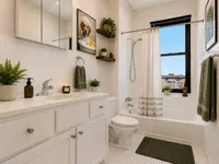 Bright and inviting bathroom with elegant white cabinetry, modern fixtures, and chic decor accentuated by plants and an artful canine portrait.