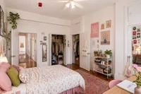Charming bedroom with floral bedding, elegant wall art, and abundant natural light in a cozy apartment.
