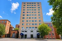 Charming apartment building in a vibrant neighborhood, showcasing a classic brick facade framed by lush green trees under a bright blue sky.