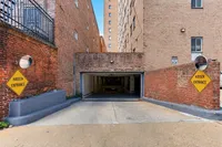 Charming brick-walled entrance to a secure underground parking area, highlighted by 'Hidden Entrance' signs for convenience and privacy.