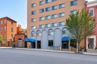 Elegant urban apartment exterior with brick facade and charming blue awnings, offering a stylish and vibrant city living experience.