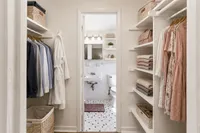 Elegant walk-in closet leading to a chic bathroom, with beautifully organized shelving and stylish attire.