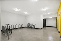 Modern indoor bike storage area with sleek metal racks and vibrant yellow accent wall, providing convenient and secure parking for cyclists.