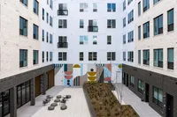 Modern apartment complex with stylish urban courtyard, featuring artistic wall mural and comfortable outdoor seating area.
