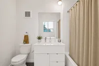 Bright and modern bathroom featuring a sleek white vanity, elegant tile flooring, and a spacious bathtub with a chic curtain.