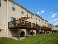 Charming multi-unit apartment building with cozy wooden decks and lush green lawns, perfect for outdoor relaxation.